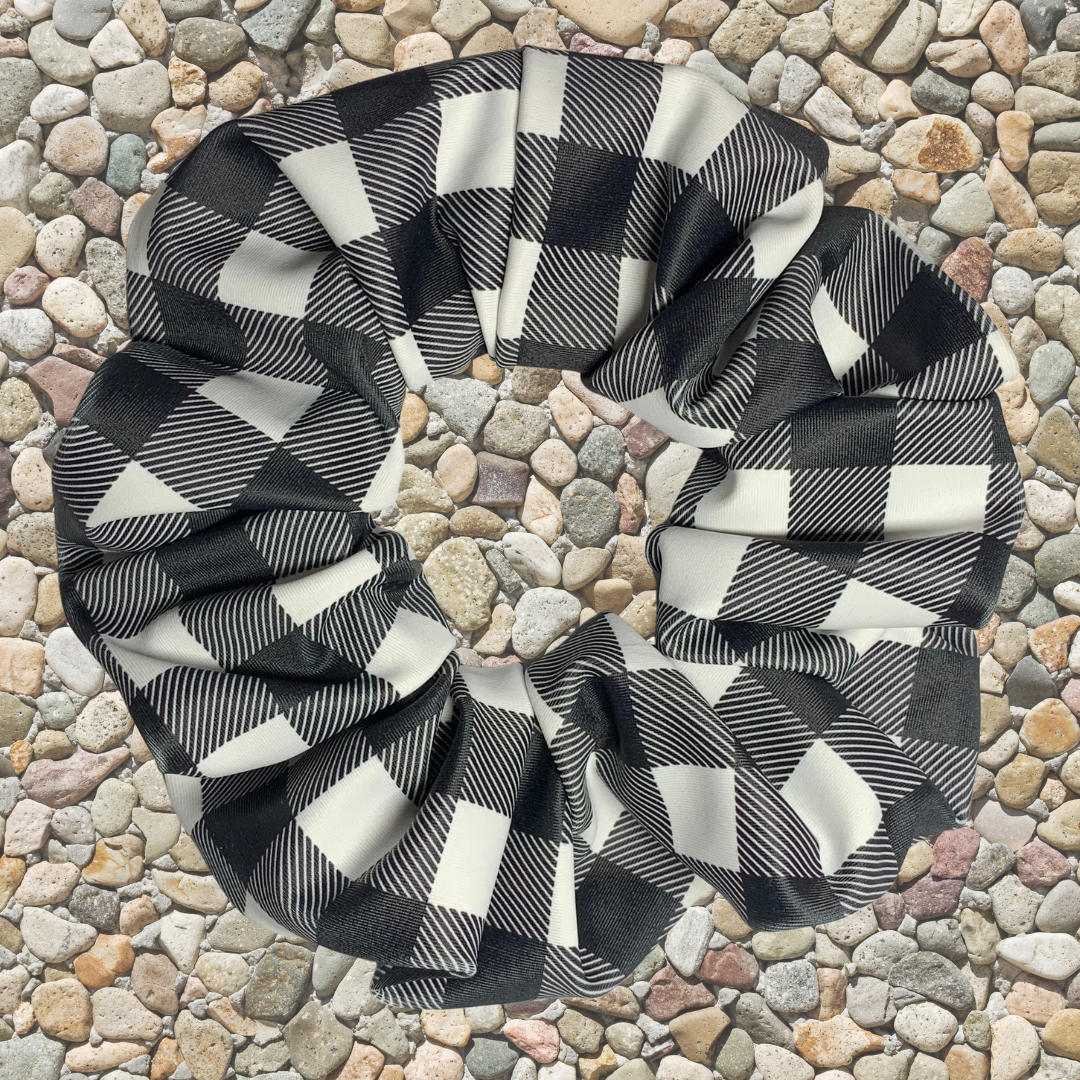 Black and white checkered patterned swim scrunchie on a pebble surface