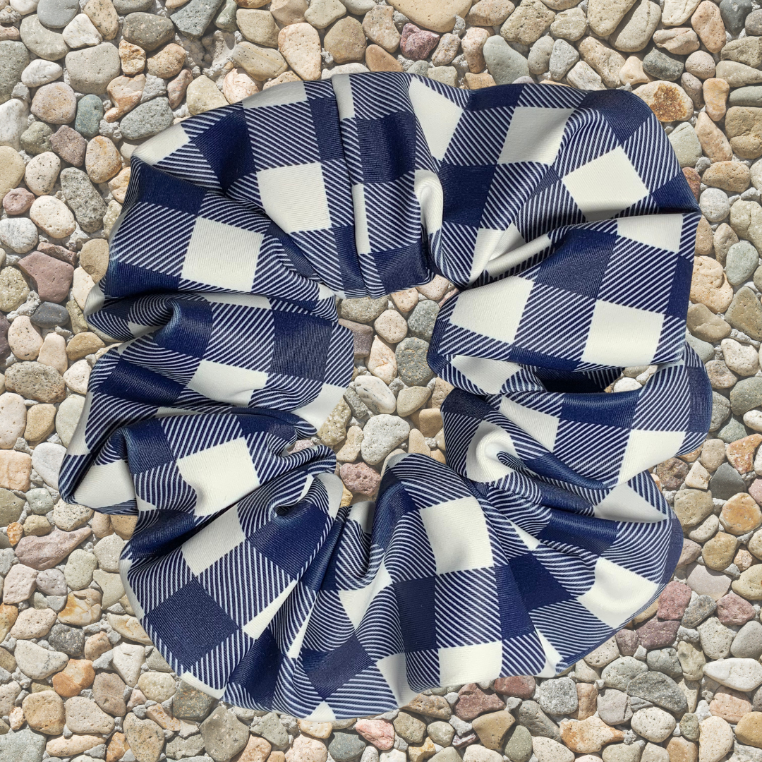 Blue and white checkered swim scrunchie on a pebble background