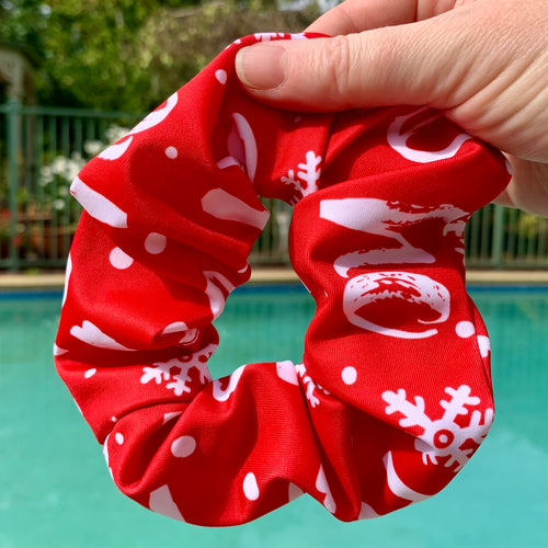 Christmas Red swim scrunchie with white ho ho ho held in front of a pool with garden in background