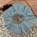sky Blue scrunchie with pebbles on a textured surface