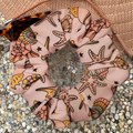 Pink scrunchie with shells and star fish designs on a textured surface