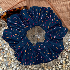 Navy blue scrunchie with colorful sprinkles on a textured surface