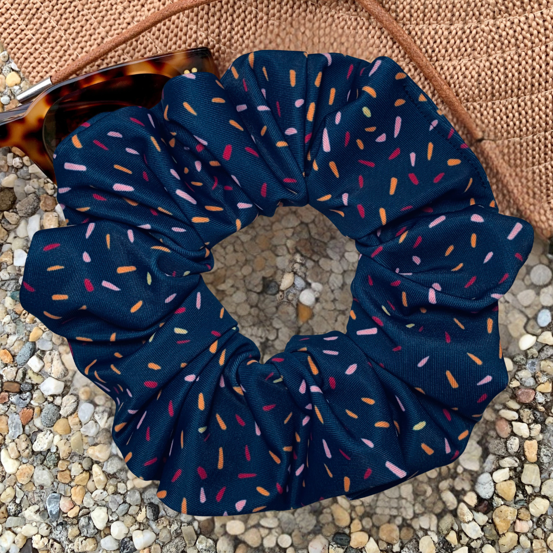 Navy blue scrunchie with colorful sprinkles on a textured surface
