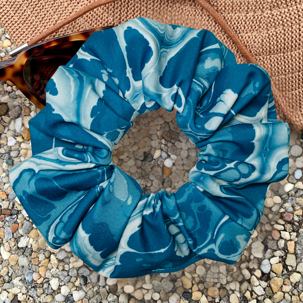 Blue and white marbled scrunchie on a textured surface