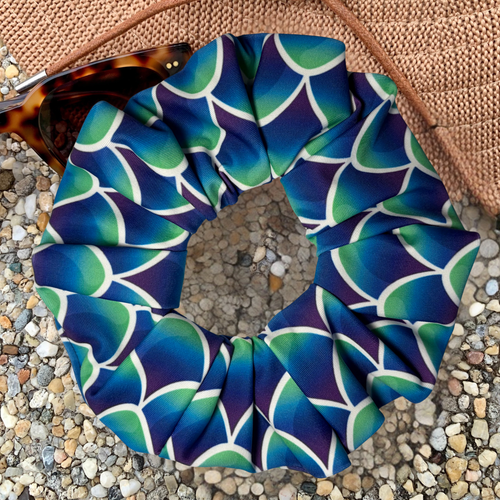 Blue and green mermaid patterned scrunchie on a textured surface