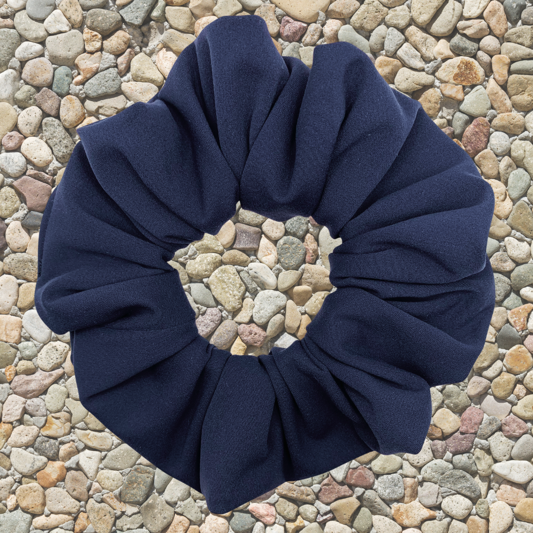 Navy blue scrunchie on a pebble background
