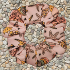 Pink scrunchie with starfish design on a pebble background