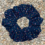 Navy blue scrunchie with colorful sprinkles on a pebble background