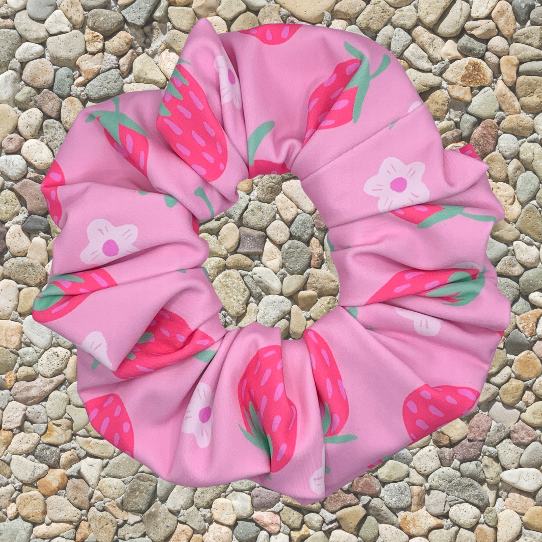 Pink scrunchie with strawberry pattern on a pebble background