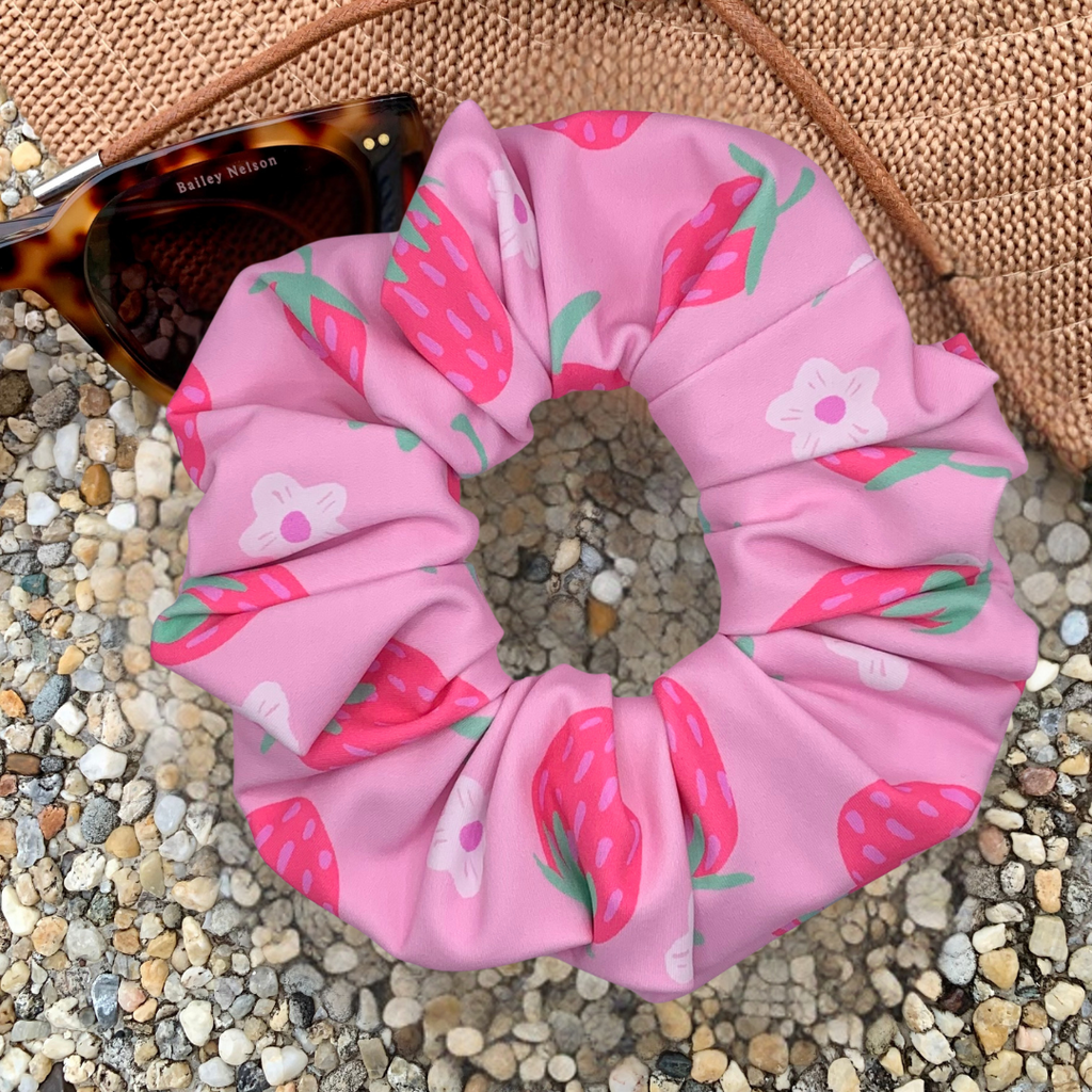 Pink scrunchie with strawberry pattern on a pebbly surface