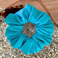 Blue scrunchie on a textured surface with sunglasses in the background