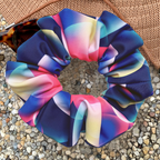 Neon bubble pattern swim scrunchie on pebble surface sitting on hat and sunglasses
