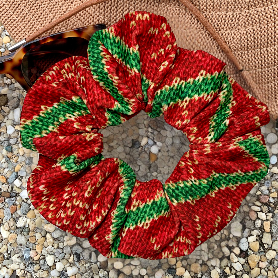 red and green christmas snowflake swim scrunchie on a pebble surface