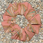 Pink seashell swim scrunchie on a pebble background