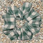 Green and white checkered swim scrunchie on a stone surface
