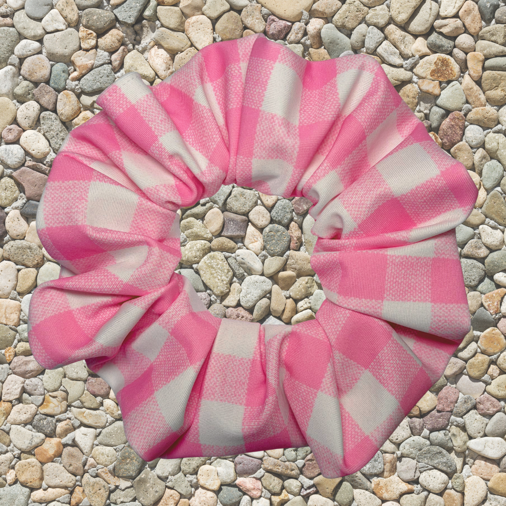 Pink and white checkered scrunchie on a pebbled surface