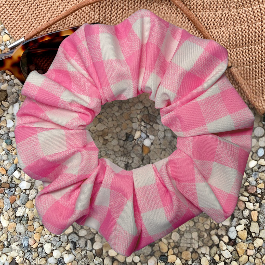 Pink and white checkered scrunchie on a textured surface
