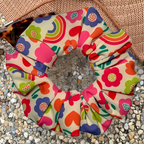 Colourful floral and heart patterned swim scrunchie on a textured surface