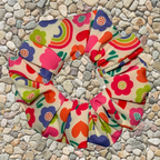 Colourful floral and rainbow patterned fabric on a pebble background