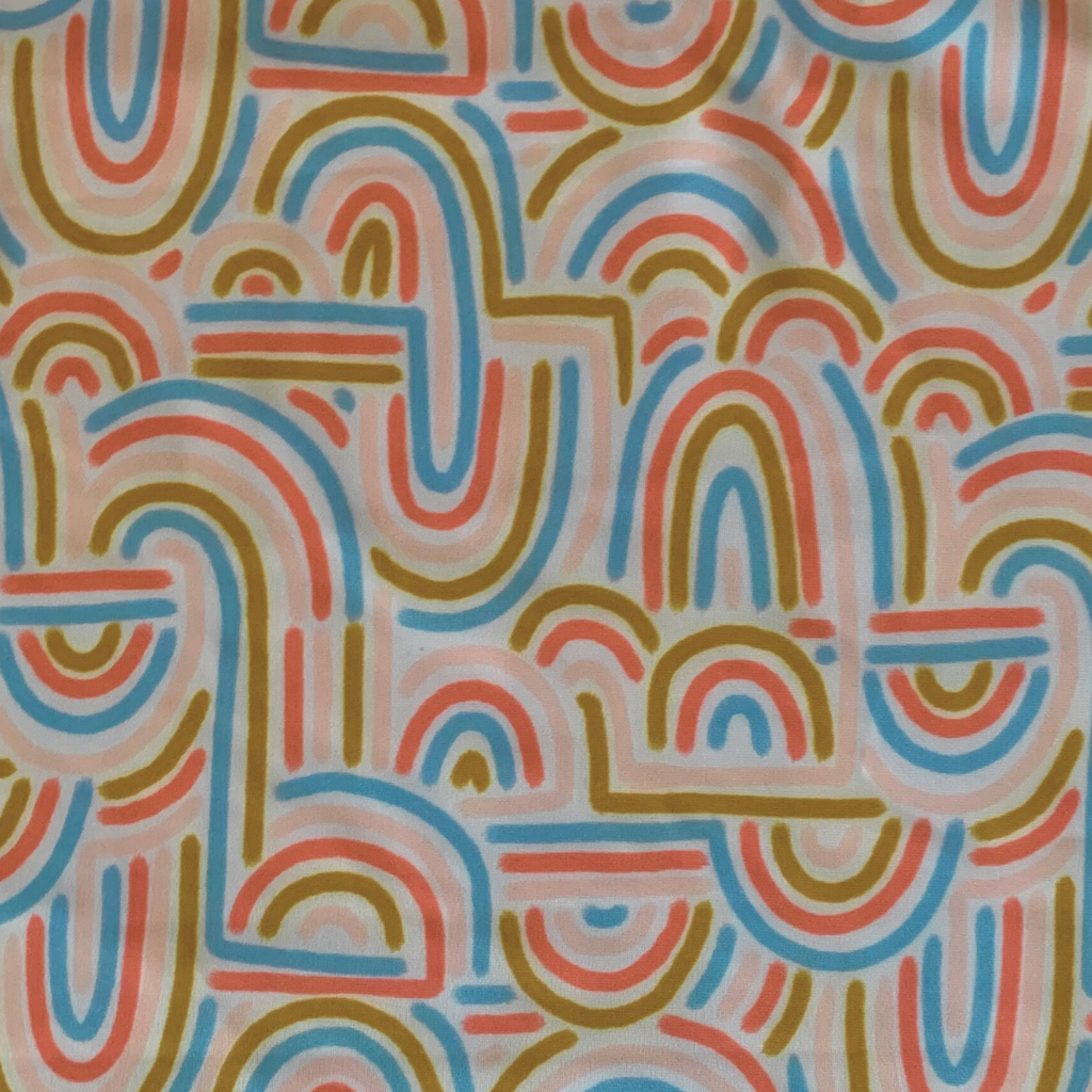 Patterned fabric with colourful abstract rainbow shapes on a pink background