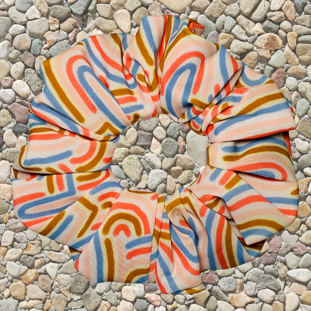 Colourful striped swim scrunchie on a pebble surface