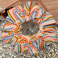 Colourful scrunchie with abstract rainbow pattern on a textured surface