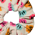 Close up of Swim scrunchie with colourful shell pattern on a white background