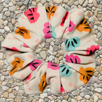Swim scrunchie with colourful shell pattern on a stone surface