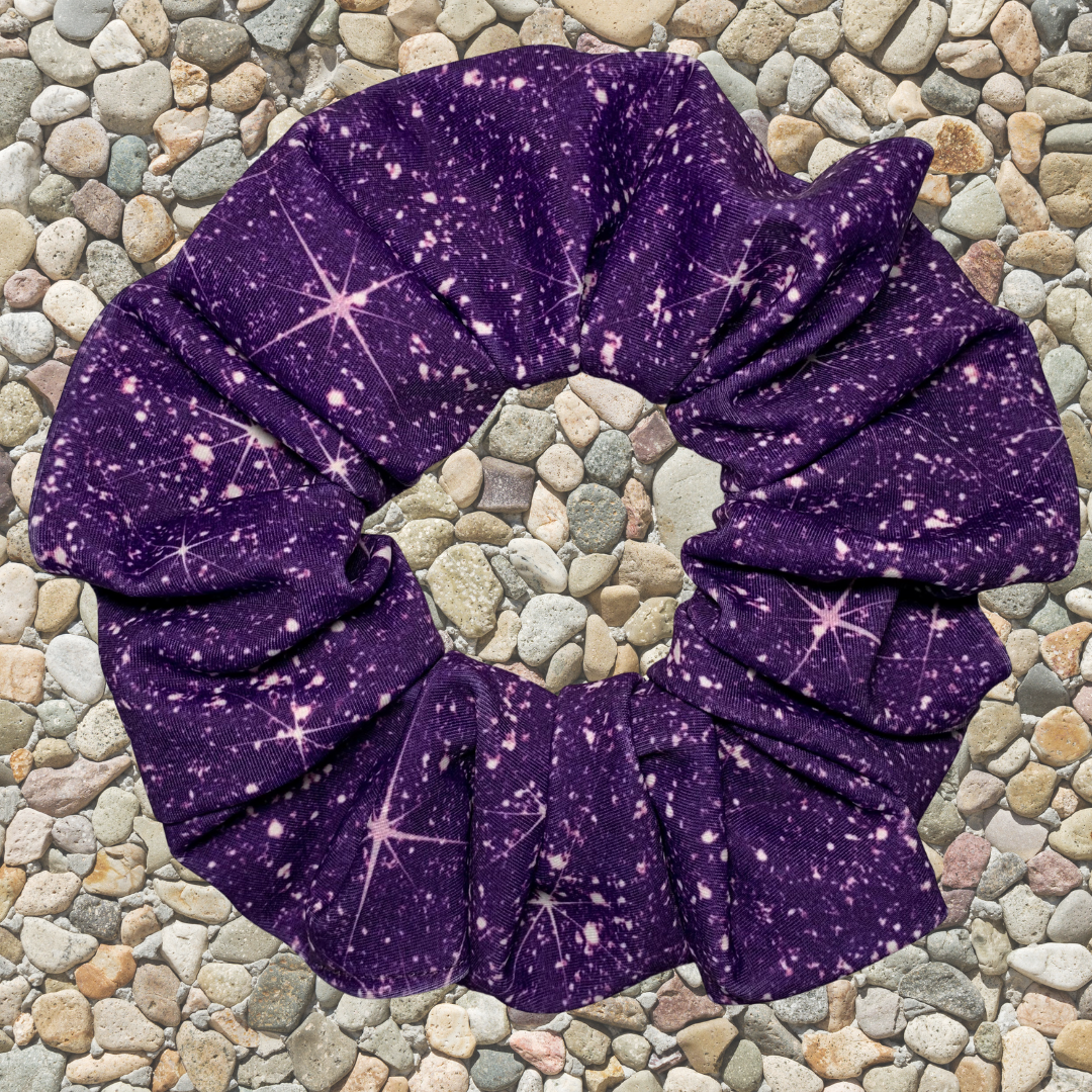 Purple printed sparkle swim scrunchie  on a pebble background