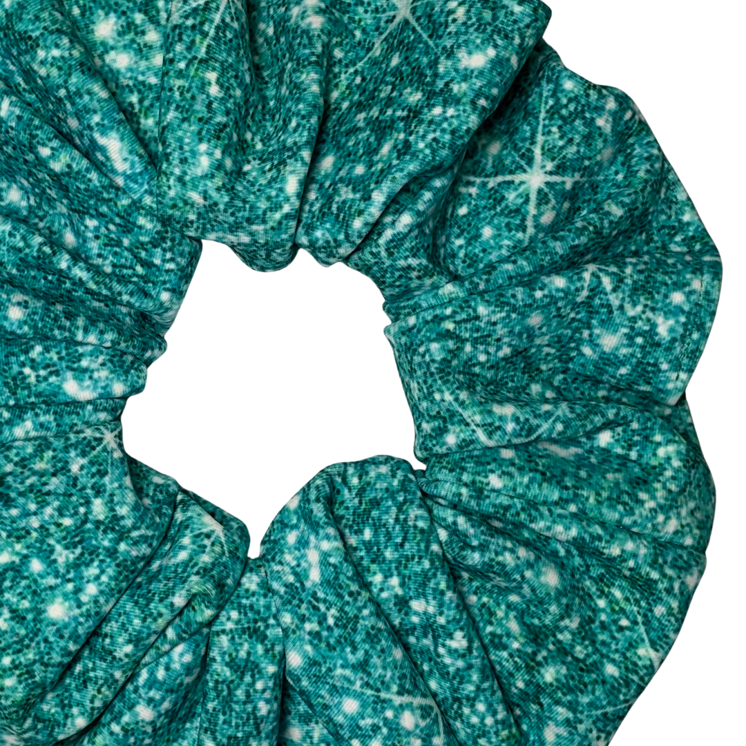 Close up of a Teal printed sparkle swim scrunchie on a white background