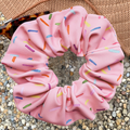 Pink swim scrunchie with colourful sprinkles on a textured surface