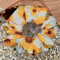 Sunflower patterned swim scrunchie on a textured surface with a hat and sunglasses